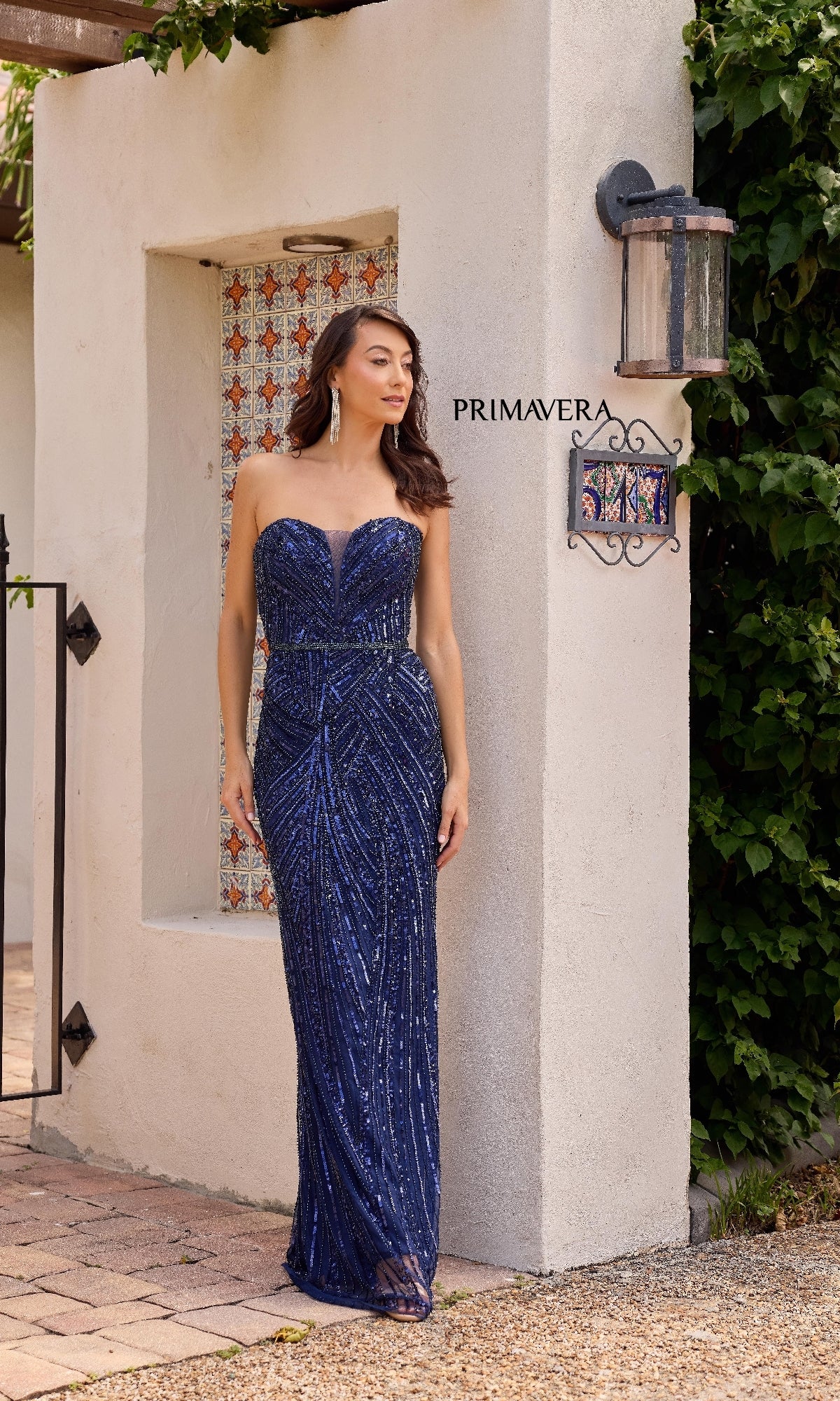 A woman stands outdoors wearing the Primavera 13141—a long, strapless navy blue sequin gown with a fitted silhouette and sweetheart neckline, perfect for making a statement at any event.